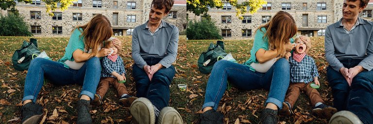 Pregnant mother, father, and son sitting on grass as mother wipes and cleans up sons face.