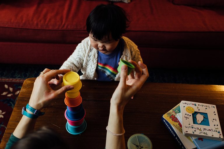 Mother and son play with stacking cups in living room.