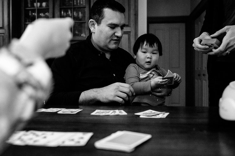 Black and white. Father and son play a game of cards at dinner table.