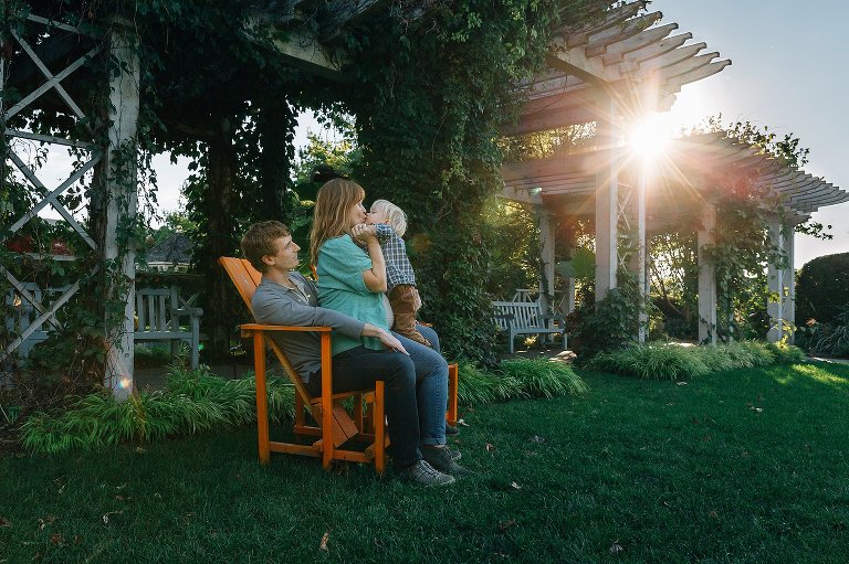 Father, mother and son sit outside on an orange bench.