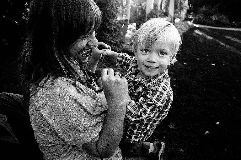 Black and white. Mother holds young boys arms both laughing.