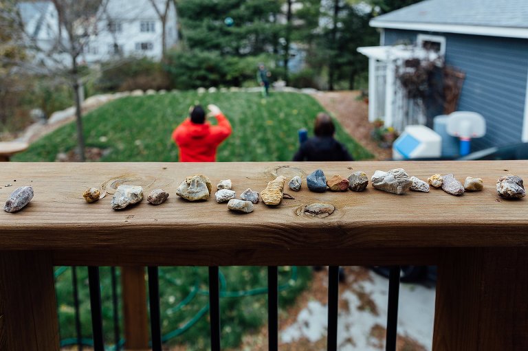 Rocks placed on balcony railing. family playing in backyard.