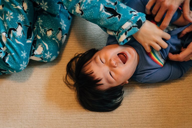 Mother and and son tickle little brother.