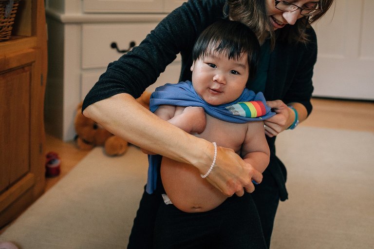 Mother puts shirt onto young son.
