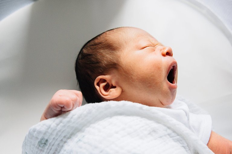 Baby yawns while laying in bassinet.
