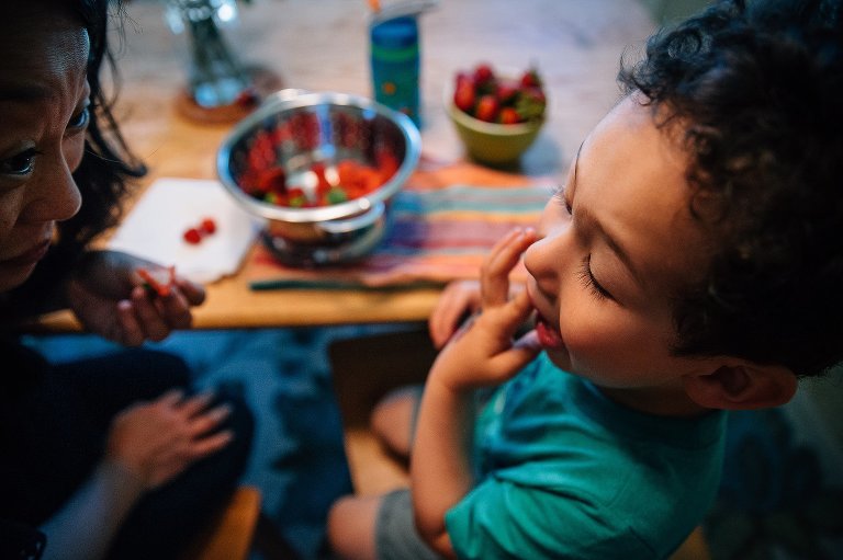 Expecting mother eats strawberries with her young son.