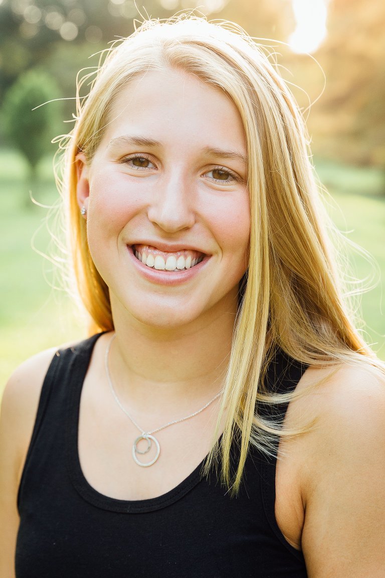 Brown eyed high school girl is camera aware and smiles for senior picture. 