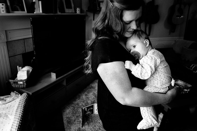 Black and white. Mother holds sleepy infant daughter. 