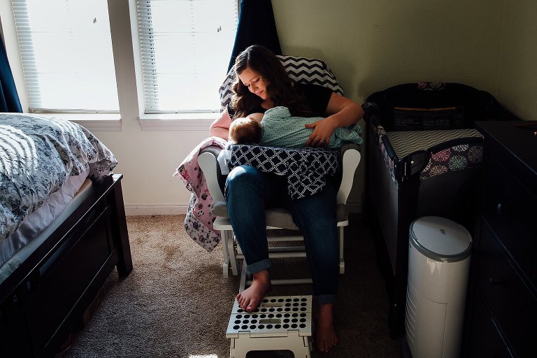Mother nurses infant daughter in a quiet bedroom. 