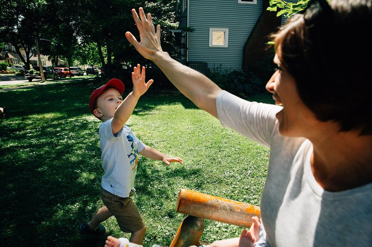 Mother gives her son a high five while he plays outside in the yard.