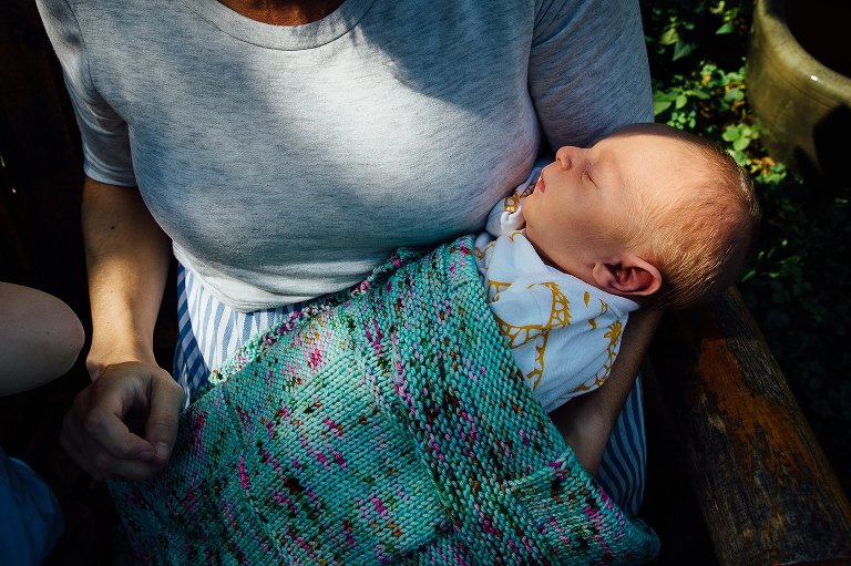 Mom sitting outside with sleeping newborn baby in her arms.