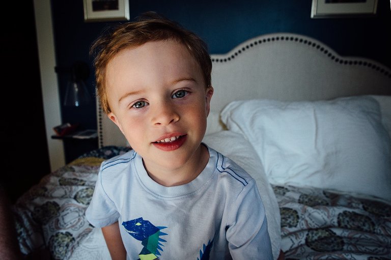 Young boy sitting on parents bed.