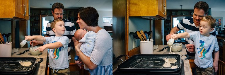 Dad helps son pour pancake batter onto the griddle. Young boy shows his mom holding a newborn baby the pancakes