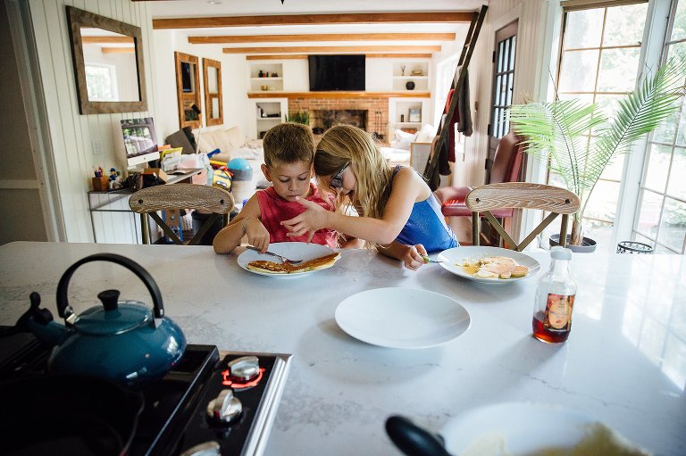 Brother and sister eat blueberry pancakes together.