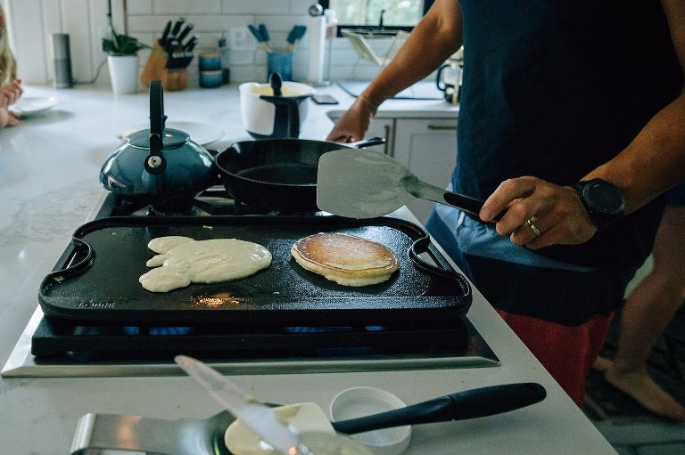 Dad flips golden brown pancakes on the griddle for breakfast.