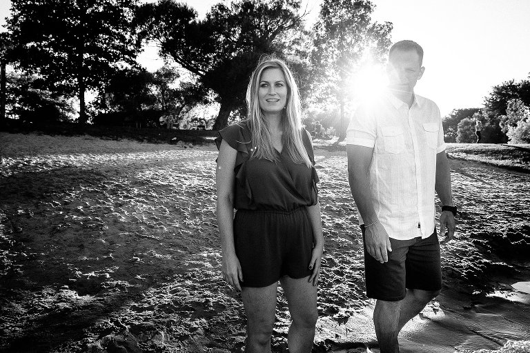 Mother and father standing at the beach with the sun setting behind them.