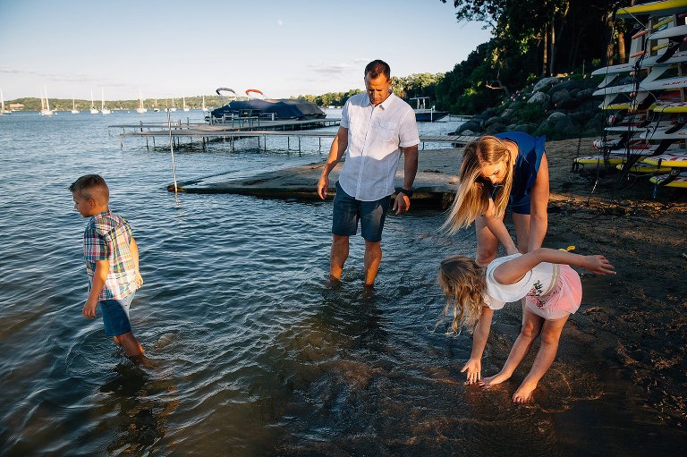 Family of four standing at the beach with their feet in the water.