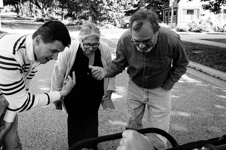 Two men point to an older woman, a grandma, while the stroller indicates the kids are looking at their grandparents. 
