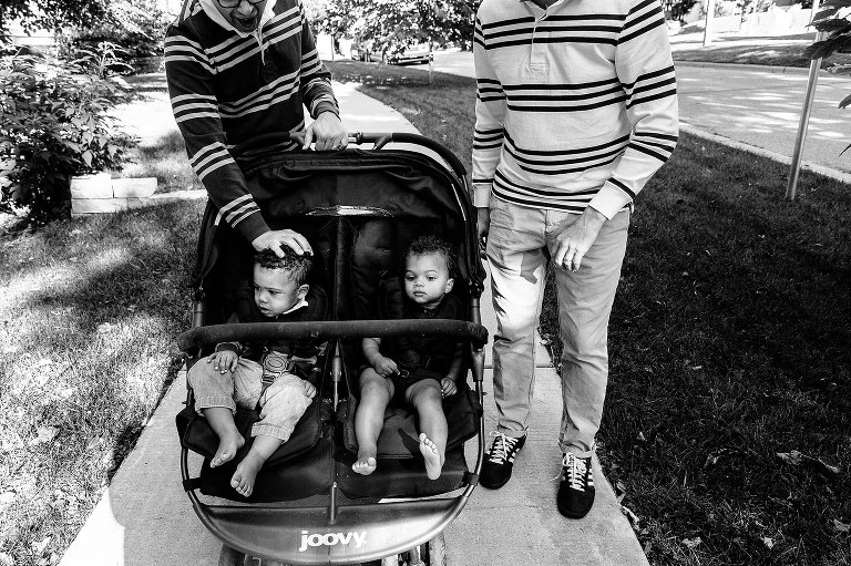 black and white. One dad puts his hand on his son's head. 