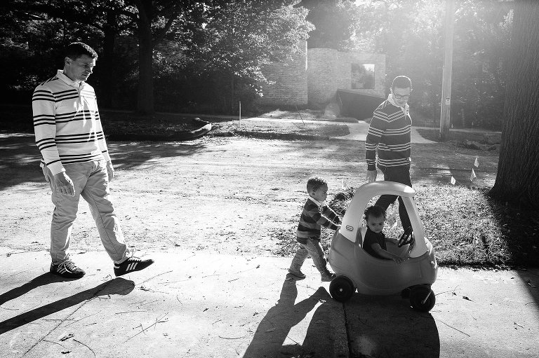 Family of four walks down the street in the sunshine. Black and white. 