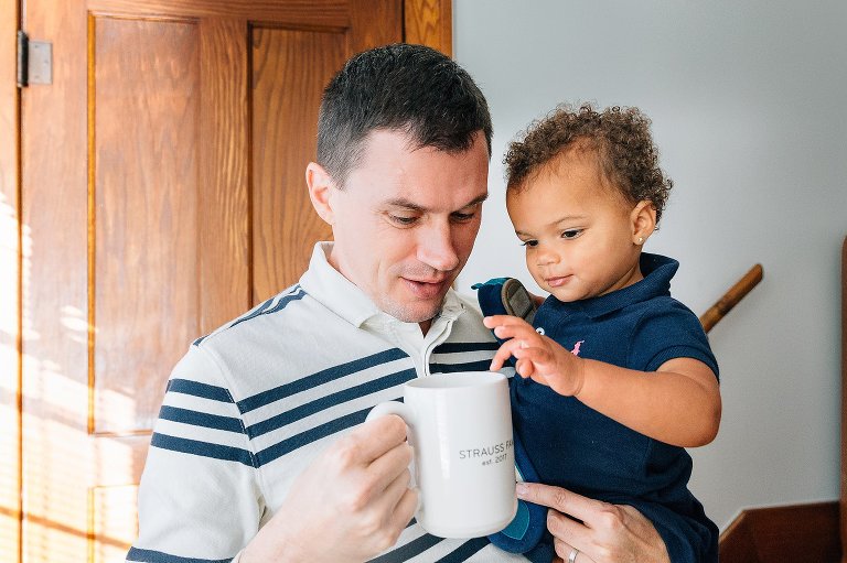 Daughter is interested in dad's coffee mug. 