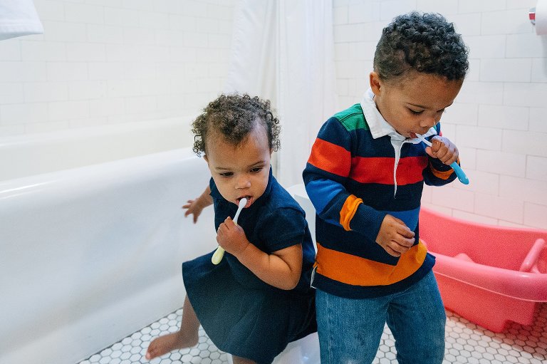 A boy and girl toddler brush teeth in the bathroom. 