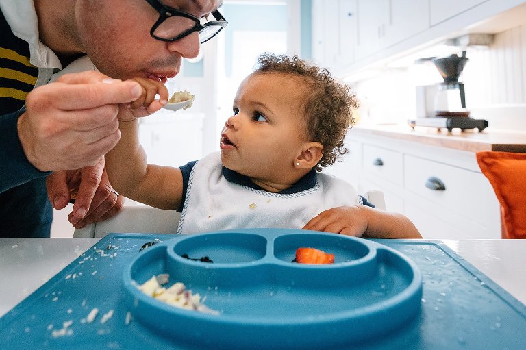 Dad blows on eggs to cool them down, daughter looks on 