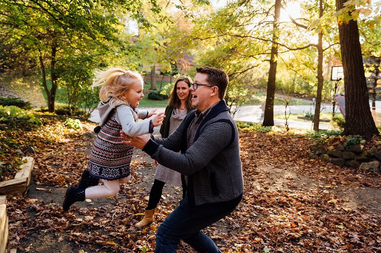 girl jumps into her dad's arms on an autumn night at home 