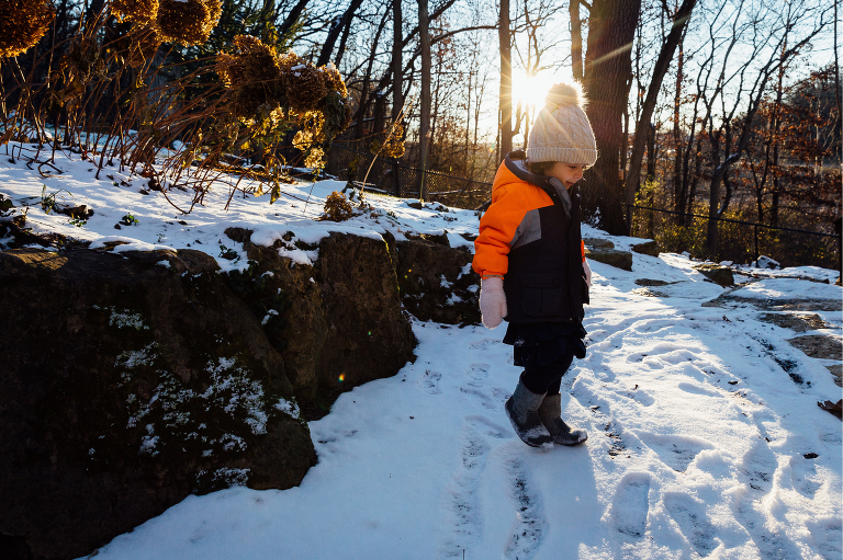 Girl walks in snow with sun setting behind her