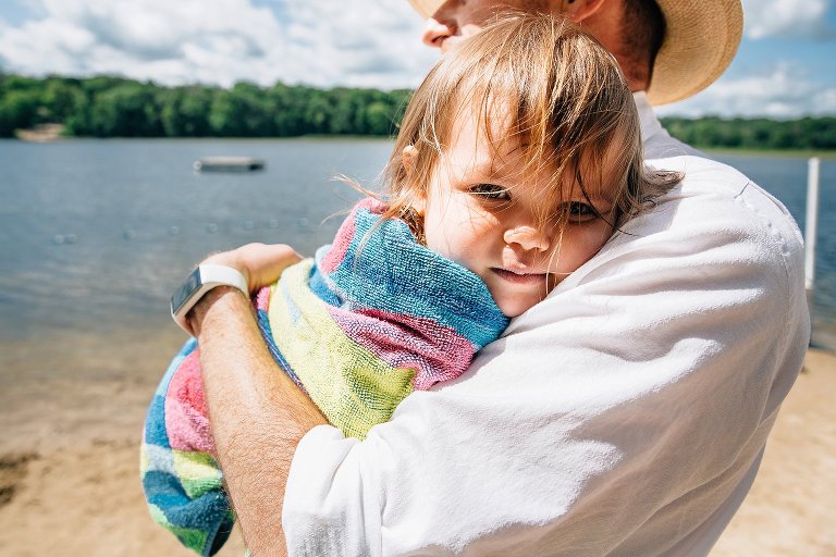 Eye contact from 2 yo being held by dad, wrapped in a colorful towel at the beach. 