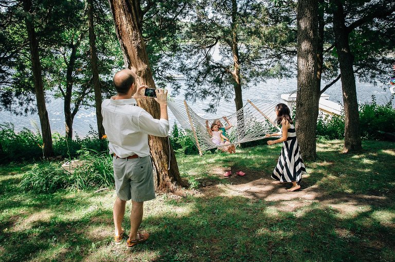 Mom swings girls in hammock, which overlooks the lake, while dad videos the laughter from his iPhone.