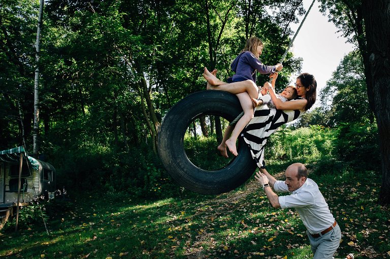 Dad pushes mom, two kids on a tire swing. 