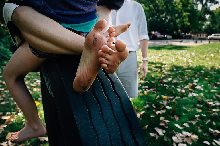 Focus on feet of several people sitting on a tire swing.