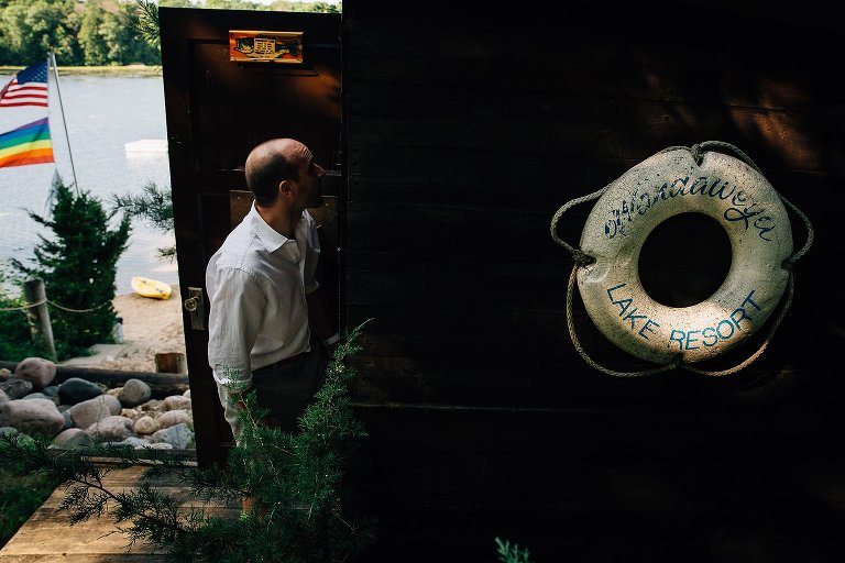 Focus on old life preserver with camp name attached to boat shed. Dad in the background, looking in shed. 