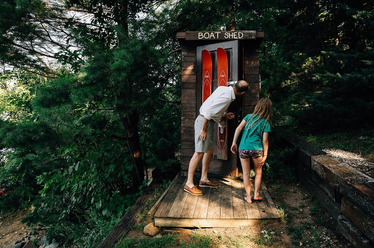 Dad and girl peek in a boat shed.