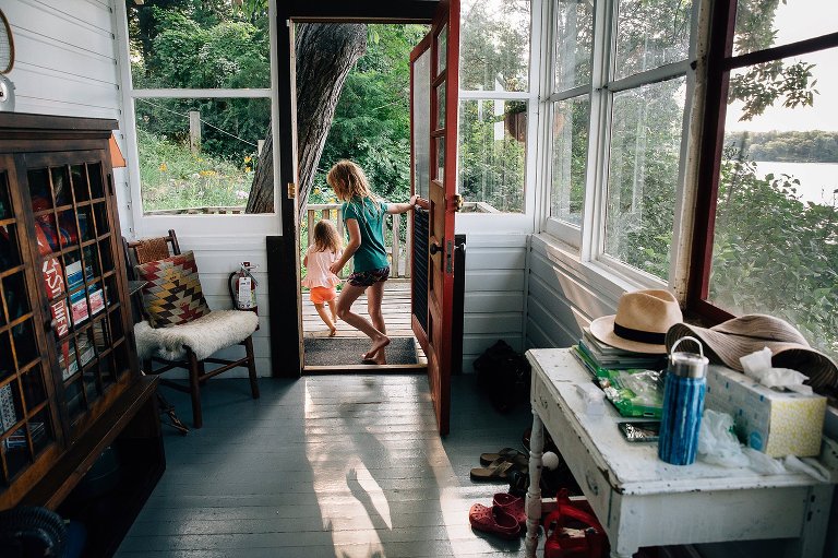 Two young girls run out the screen door of a cabin. One shadow falls cleanly on the floor.
