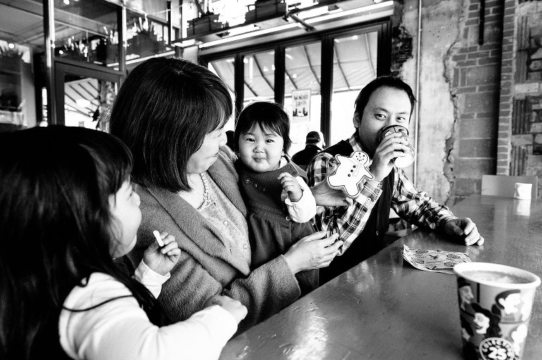 Family of four eats a snowman cookie in a coffee shop window. 
