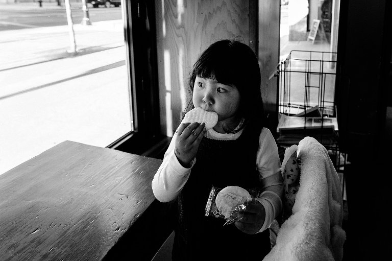 4yo girl rice cracker in window light. Black and white.