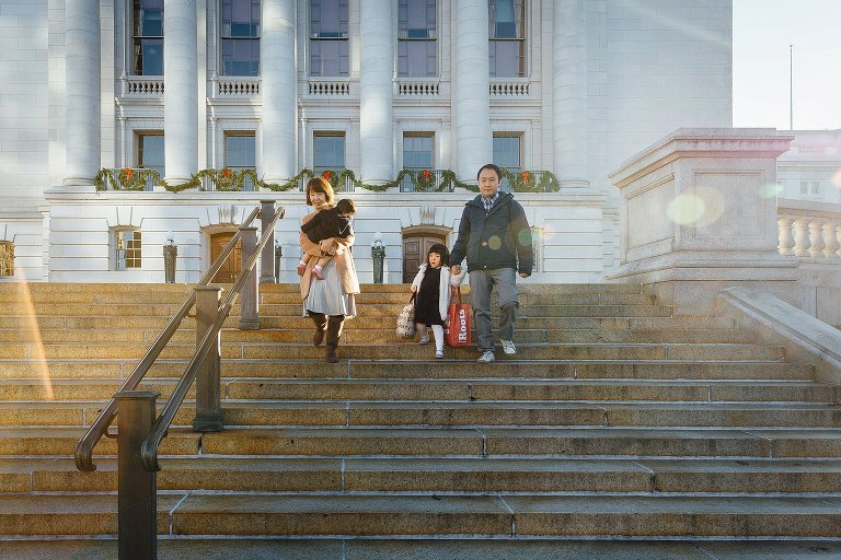 Family of four walk down the stairs at the Wisconsin State Capitol building. 
