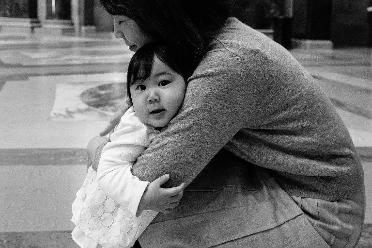 Black and white. one year old girl hugs her mother and makes eye contact with camera