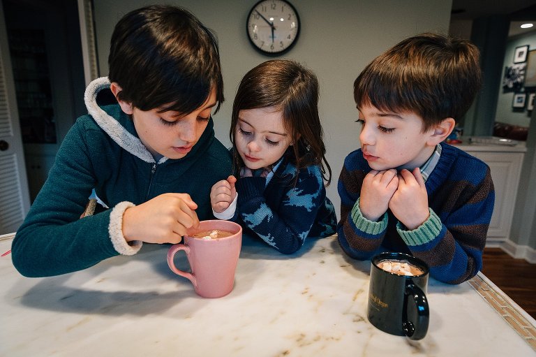 3 kids count marshmallows in their hot chocolate.