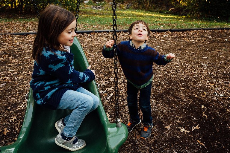 5yo dances while 5yo sister sits on swing.