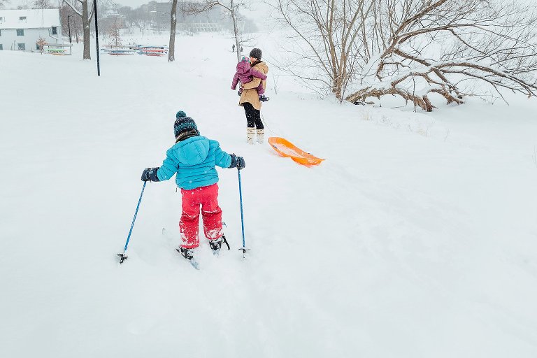 Young girl learns to ski while mother nad young sister look on.