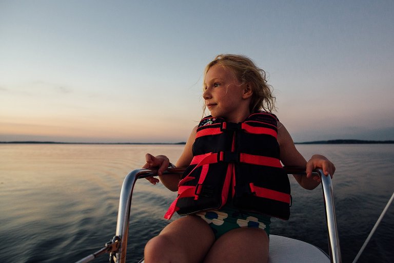 Girl sits in captains chair on sailboat at sunset. gentle breeze blows her hair.  Madison family photographer