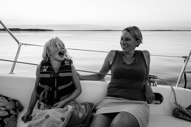 Black and white. Mom and daughter laughing on sailboat at dusk. very low light. madison family photographer