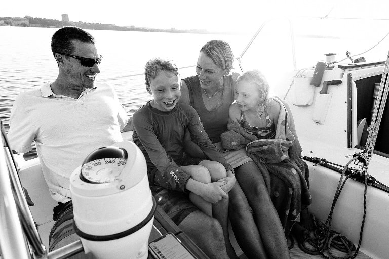 Black and white. Family on sailboat, connecting with each other.