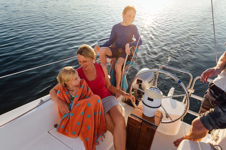 Mom, daughter, son, on sailboat at sunset. Very colorful.