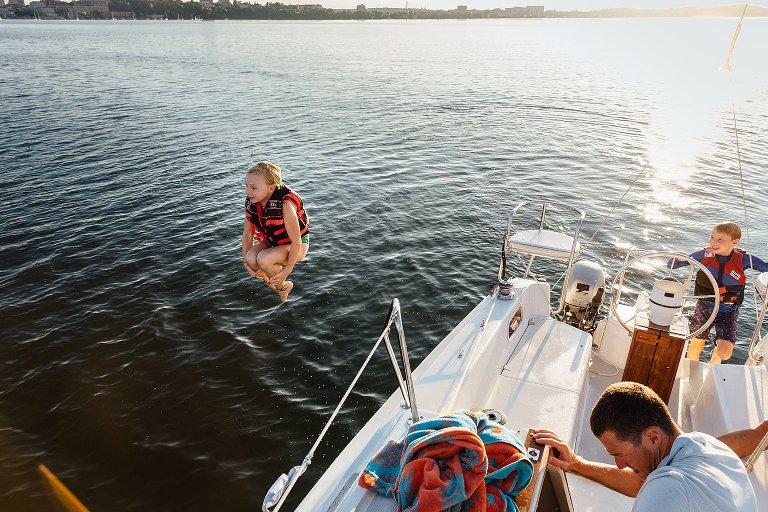 Girl does cannon ball into the lake at sunset.