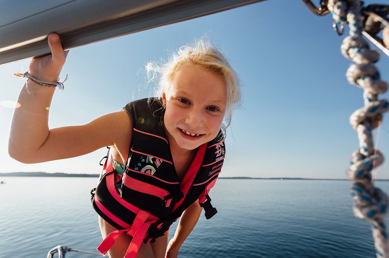 young girl looks under the sail beam on a sailboat