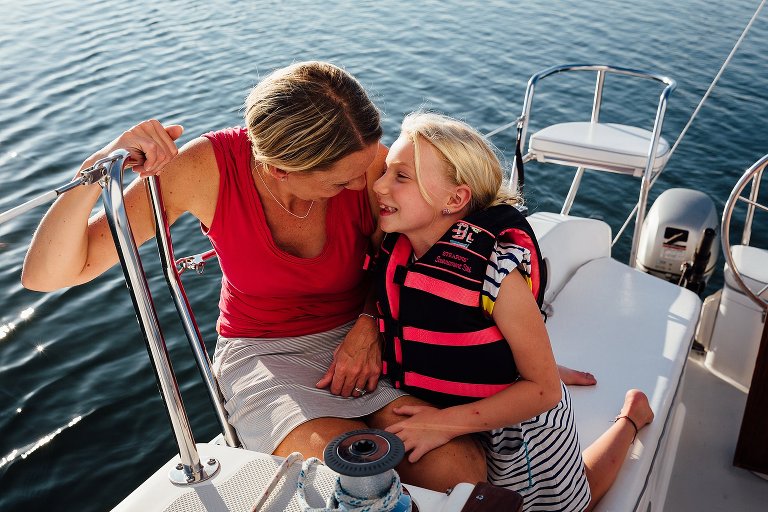 Mother and daughter on a sailboat, laughing.